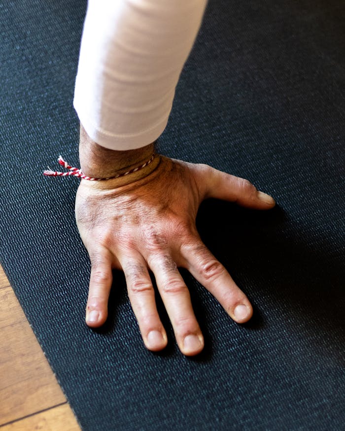 Detailed image of a hand pressing onto a yoga mat, symbolizing strength and mindfulness.